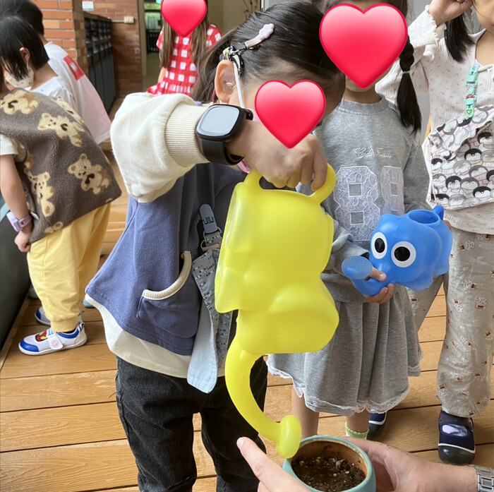 在老師的協助下，孩子小心地為植物澆水，學習用愛心照顧生命圖片